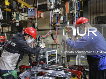 Workers work on the production line at the production workshop of Qingdao Wushun Auto Mold Parts Co., LTD., in West Coast New Area, Qingdao,...