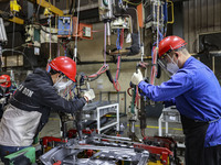 Workers work on the production line at the production workshop of Qingdao Wushun Auto Mold Parts Co., LTD., in West Coast New Area, Qingdao,...