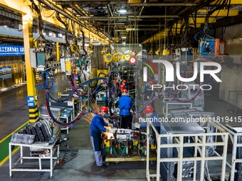 Workers work on the production line at the production workshop of Qingdao Wushun Auto Mold Parts Co., LTD., in West Coast New Area, Qingdao,...