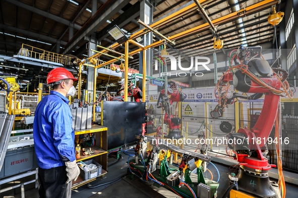 Workers work on the production line at the production workshop of Qingdao Wushun Auto Mold Parts Co., LTD., in West Coast New Area, Qingdao,...