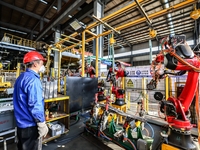 Workers work on the production line at the production workshop of Qingdao Wushun Auto Mold Parts Co., LTD., in West Coast New Area, Qingdao,...