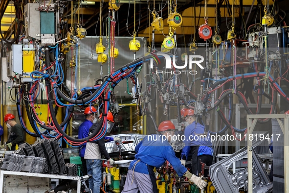 Workers work on the production line at the production workshop of Qingdao Wushun Auto Mold Parts Co., LTD., in West Coast New Area, Qingdao,...