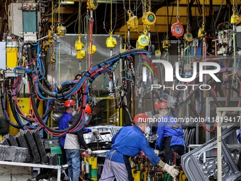 Workers work on the production line at the production workshop of Qingdao Wushun Auto Mold Parts Co., LTD., in West Coast New Area, Qingdao,...