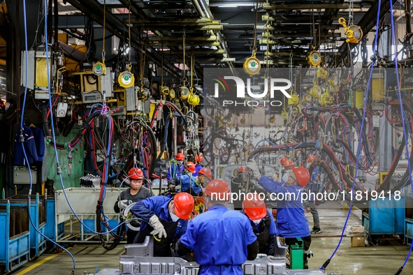 Workers work on the production line at the production workshop of Qingdao Wushun Auto Mold Parts Co., LTD., in West Coast New Area, Qingdao,...