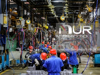 Workers work on the production line at the production workshop of Qingdao Wushun Auto Mold Parts Co., LTD., in West Coast New Area, Qingdao,...