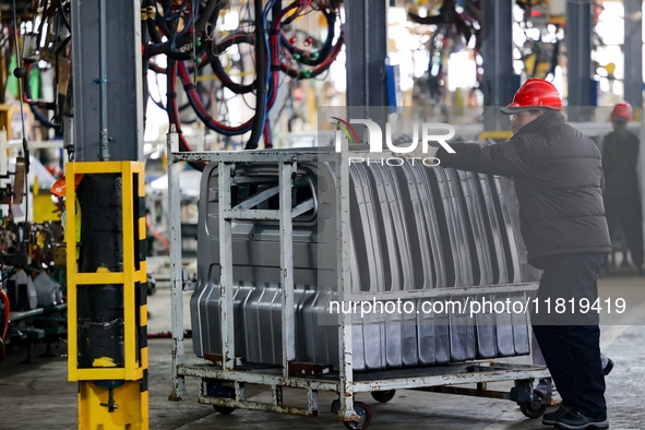 Workers work on the production line at the production workshop of Qingdao Wushun Auto Mold Parts Co., LTD., in West Coast New Area, Qingdao,...