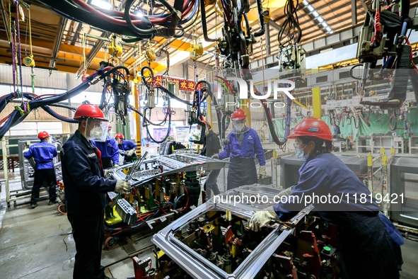 Workers work on the production line at the production workshop of Qingdao Wushun Auto Mold Parts Co., LTD., in West Coast New Area, Qingdao,...