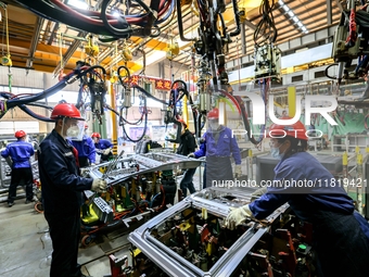 Workers work on the production line at the production workshop of Qingdao Wushun Auto Mold Parts Co., LTD., in West Coast New Area, Qingdao,...