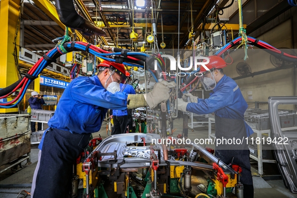 Workers work on the production line at the production workshop of Qingdao Wushun Auto Mold Parts Co., LTD., in West Coast New Area, Qingdao,...