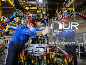 Workers work on the production line at the production workshop of Qingdao Wushun Auto Mold Parts Co., LTD., in West Coast New Area, Qingdao,...