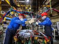 Workers work on the production line at the production workshop of Qingdao Wushun Auto Mold Parts Co., LTD., in West Coast New Area, Qingdao,...