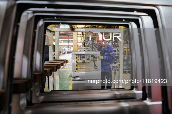 Workers work on the production line at the production workshop of Qingdao Wushun Auto Mold Parts Co., LTD., in West Coast New Area, Qingdao,...