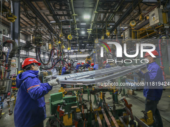 Workers work on the production line at the production workshop of Qingdao Wushun Auto Mold Parts Co., LTD., in West Coast New Area, Qingdao,...