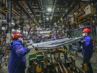 Workers work on the production line at the production workshop of Qingdao Wushun Auto Mold Parts Co., LTD., in West Coast New Area, Qingdao,...