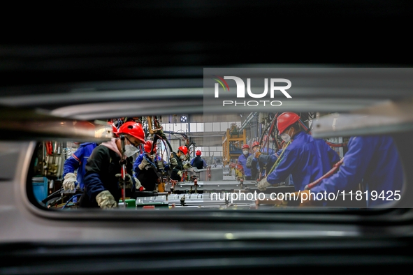 Workers work on the production line at the production workshop of Qingdao Wushun Auto Mold Parts Co., LTD., in West Coast New Area, Qingdao,...