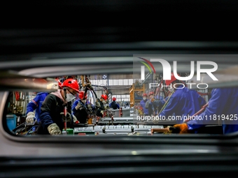 Workers work on the production line at the production workshop of Qingdao Wushun Auto Mold Parts Co., LTD., in West Coast New Area, Qingdao,...