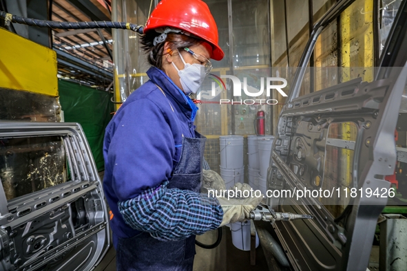 Workers work on the production line at the production workshop of Qingdao Wushun Auto Mold Parts Co., LTD., in West Coast New Area, Qingdao,...