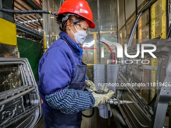 Workers work on the production line at the production workshop of Qingdao Wushun Auto Mold Parts Co., LTD., in West Coast New Area, Qingdao,...