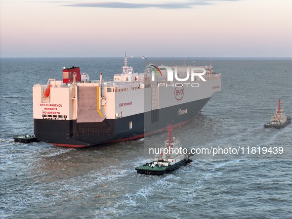 The car carrier ''BYD Changzhou'' departs with the assistance of a tugboat at CIMC Raffles' Shandong Longkou construction base in Yantai, Ch...