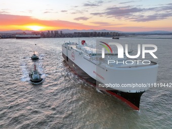 The car carrier ''BYD Changzhou'' departs with the assistance of a tugboat at CIMC Raffles' Shandong Longkou construction base in Yantai, Ch...