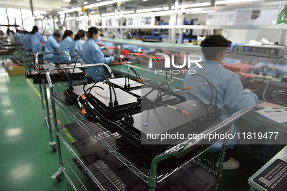 Employees work on a production line of wireless power supply products at the workshop of Zhonghui Chuangzhi (Fuyang) Technology Co., LTD in...