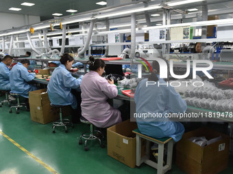 Employees work on a production line of wireless power supply products at the workshop of Zhonghui Chuangzhi (Fuyang) Technology Co., LTD in...