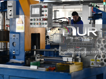 Employees work on a wire and cable production line at Anhui Aipu Huaton Electronic Technology Co LTD in Fuyang, China, on November 29, 2024....