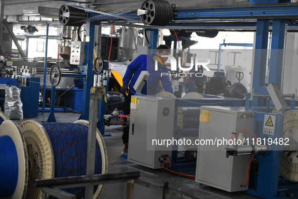 Employees work on a wire and cable production line at Anhui Aipu Huaton Electronic Technology Co LTD in Fuyang, China, on November 29, 2024....