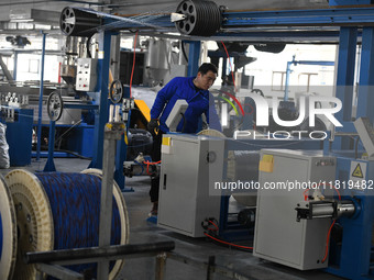 Employees work on a wire and cable production line at Anhui Aipu Huaton Electronic Technology Co LTD in Fuyang, China, on November 29, 2024....