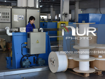 Employees work on a wire and cable production line at Anhui Aipu Huaton Electronic Technology Co LTD in Fuyang, China, on November 29, 2024....