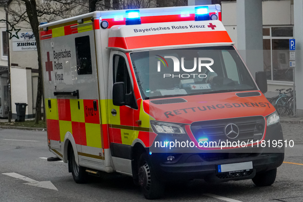 A Bavarian Red Cross ambulance, marked with bright red and yellow reflective panels, responds to an emergency with its blue lights activated...