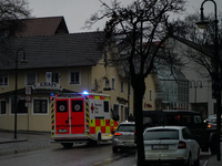 An ambulance from the Bavarian Red Cross navigates through the dimly lit Bahnhofstraße in Gauting, Germany, on January 5, 2022, with its lig...