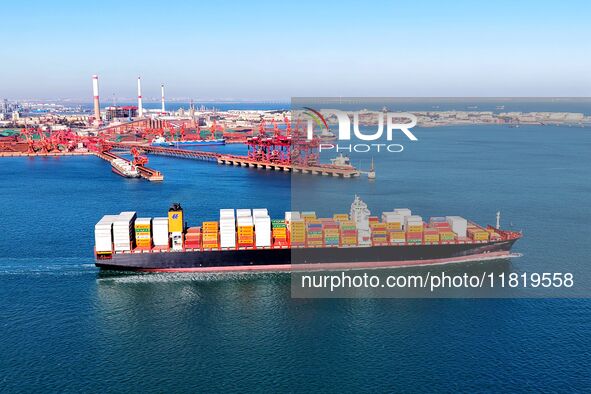 A cargo ship loaded with containers leaves the port of Qingdao in Qingdao, China, on November 29, 2024. 