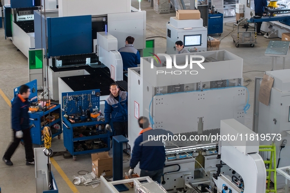 A worker produces a fiber laser cutting machine on a flexible production line in a digital production workshop in the West Coast New Area of...