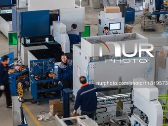 A worker produces a fiber laser cutting machine on a flexible production line in a digital production workshop in the West Coast New Area of...