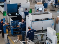 A worker produces a fiber laser cutting machine on a flexible production line in a digital production workshop in the West Coast New Area of...