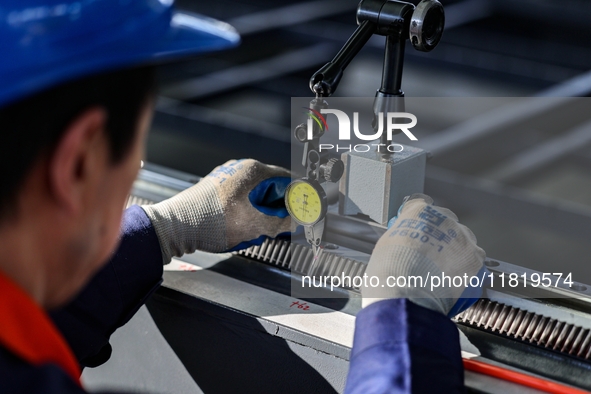 A worker produces a fiber laser cutting machine on a flexible production line in a digital production workshop in the West Coast New Area of...