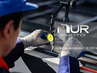 A worker produces a fiber laser cutting machine on a flexible production line in a digital production workshop in the West Coast New Area of...