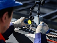 A worker produces a fiber laser cutting machine on a flexible production line in a digital production workshop in the West Coast New Area of...