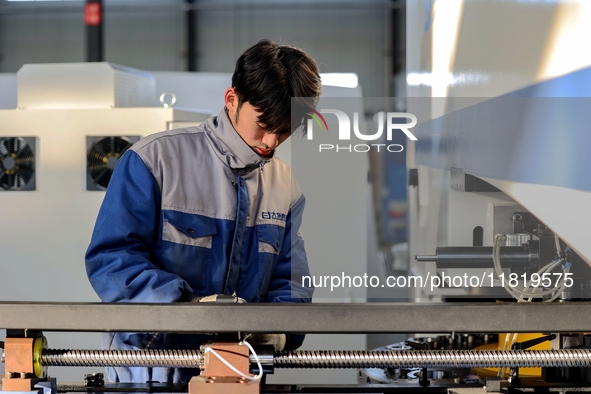 A worker produces a fiber laser cutting machine on a flexible production line in a digital production workshop in the West Coast New Area of...