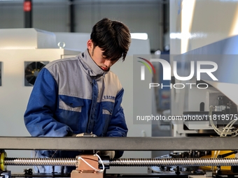 A worker produces a fiber laser cutting machine on a flexible production line in a digital production workshop in the West Coast New Area of...