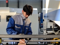 A worker produces a fiber laser cutting machine on a flexible production line in a digital production workshop in the West Coast New Area of...