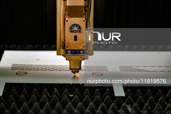 A worker produces a fiber laser cutting machine on a flexible production line in a digital production workshop in the West Coast New Area of...