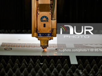 A worker produces a fiber laser cutting machine on a flexible production line in a digital production workshop in the West Coast New Area of...