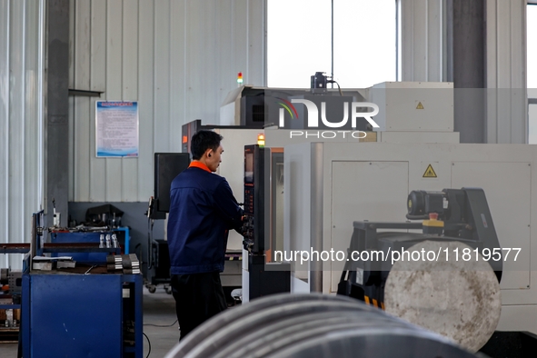 A worker produces a fiber laser cutting machine on a flexible production line in a digital production workshop in the West Coast New Area of...