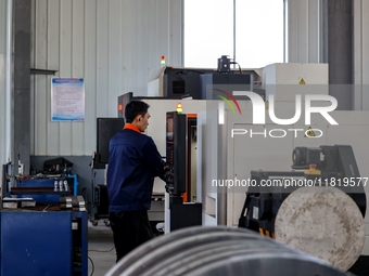 A worker produces a fiber laser cutting machine on a flexible production line in a digital production workshop in the West Coast New Area of...