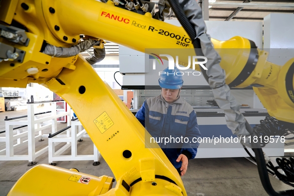 A worker produces a fiber laser cutting machine on a flexible production line in a digital production workshop in the West Coast New Area of...