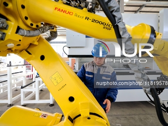 A worker produces a fiber laser cutting machine on a flexible production line in a digital production workshop in the West Coast New Area of...