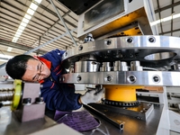 A worker produces a fiber laser cutting machine on a flexible production line in a digital production workshop in the West Coast New Area of...