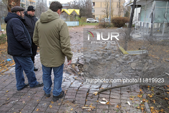 Men stand by the damaged pavement outside a family polyclinic in the Dniprovskyi district affected by an overnight Russian drone attack in K...